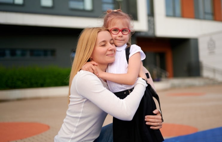 Young daughter wearing glasses hugging mother