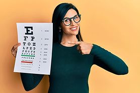 woman holding up a Snellen eye chart