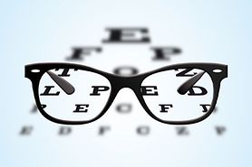 Eyeglasses with black frames positioned on an ophthalmic eye test table