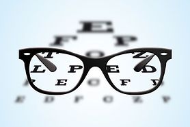 Eyeglasses with black frames positioned on an ophthalmic eye test table