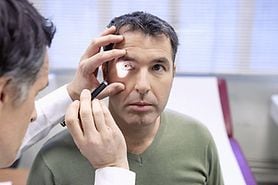 eye doctor performing a perrla eye test on patient