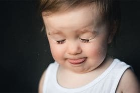 toddler closing eyes and sticking out tongue