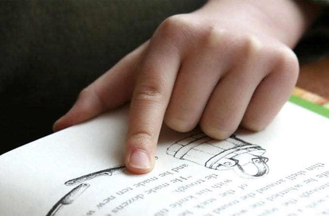 Child reading with their finger Child reading with their finger