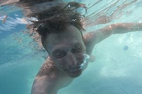 man in ocean with eyes closed due to salt water burning his eyes