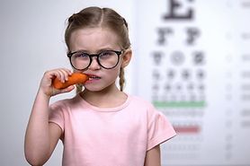 young girl eating carrots and wearing eyeglasses