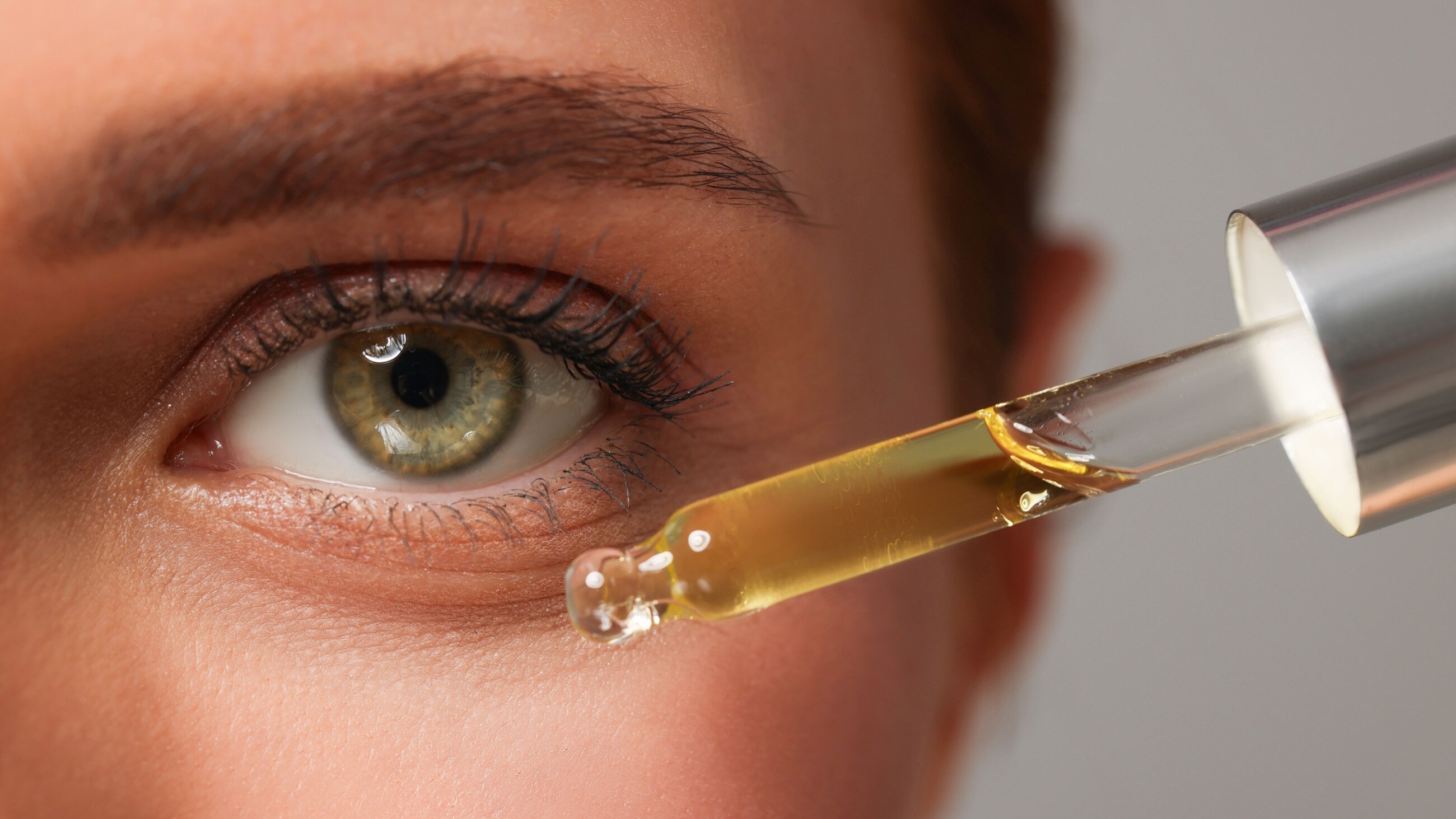 woman putting on face oil near her eyes