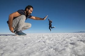 Optical illusion of giant man and small woman high-fiving.