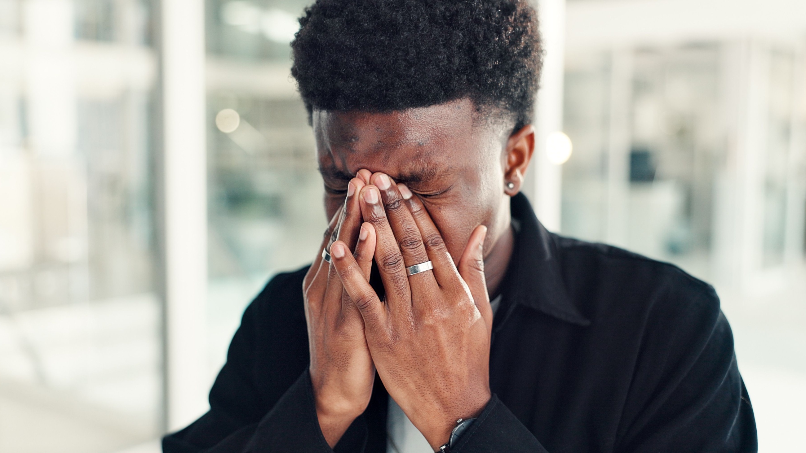 Young man with asthenopia (eye strain) rubbing his eyes.