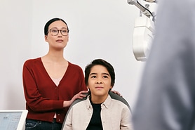 A young boy wearing glasses gets help with his homework