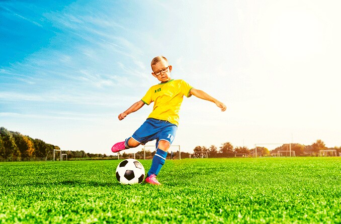 child with myopia wearing glasses and playing soccer