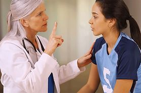 girl with a head injury getting eyes checked by a doctor