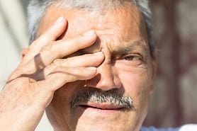 man sensitive to the bright light, which is a symptom of having cataracts