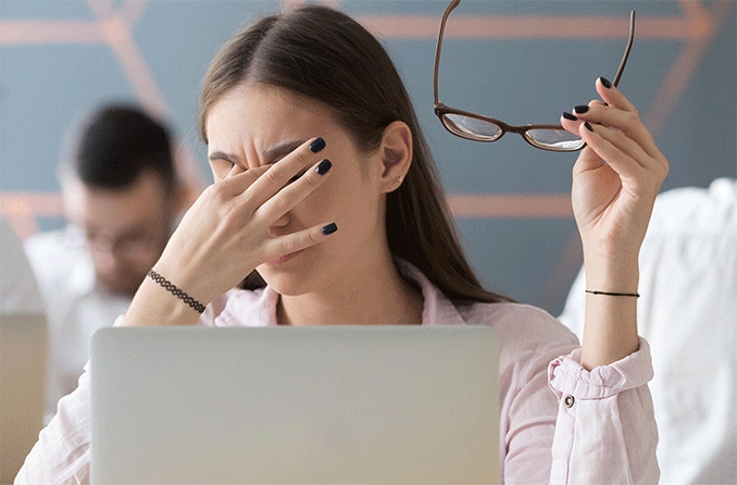 woman with dry eyes  rubbing eyes at computer