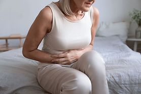 woman with poor gut health holding her stomach in discomfort