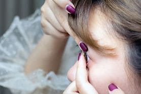 Young, dark-haired woman inserting a contact lens