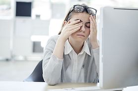 woman at a computer rubbing tired eyes