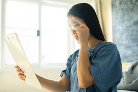 woman with blurry vision holding up something to read after having eye surgery
