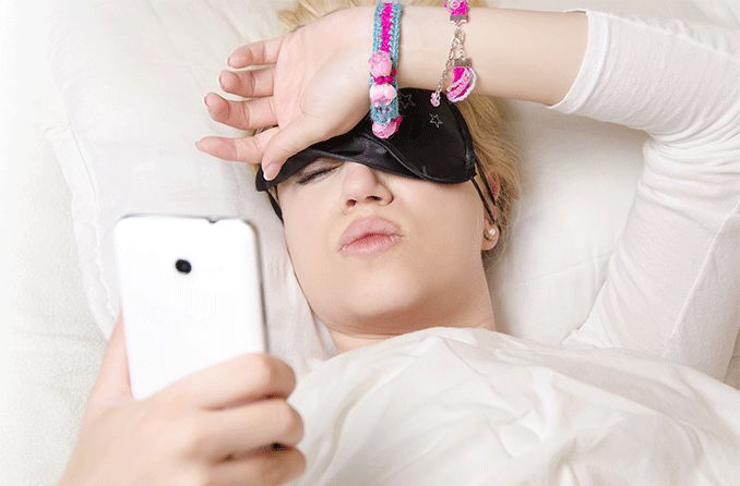 woman waking up in the morning with blurry vision looking at cell phone woman waking up in the morning with blurry vision looking at cell phone