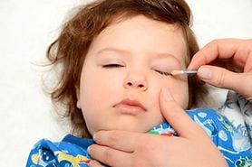 child with goopy eyes cleaning lids with a Q-tip