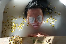 woman relaxing in a tub with compress over her eyes to naturally treat her eye floaters