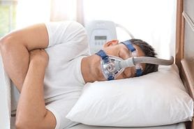 man in bed with sleep apnea wearing breathing mask