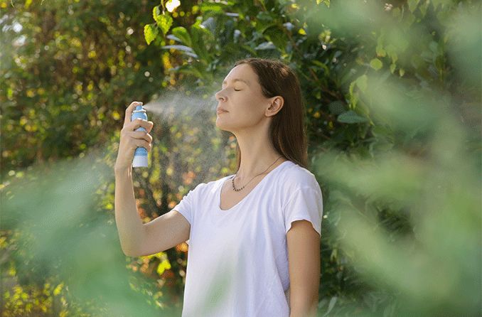 woman spraying sunscreen on her face