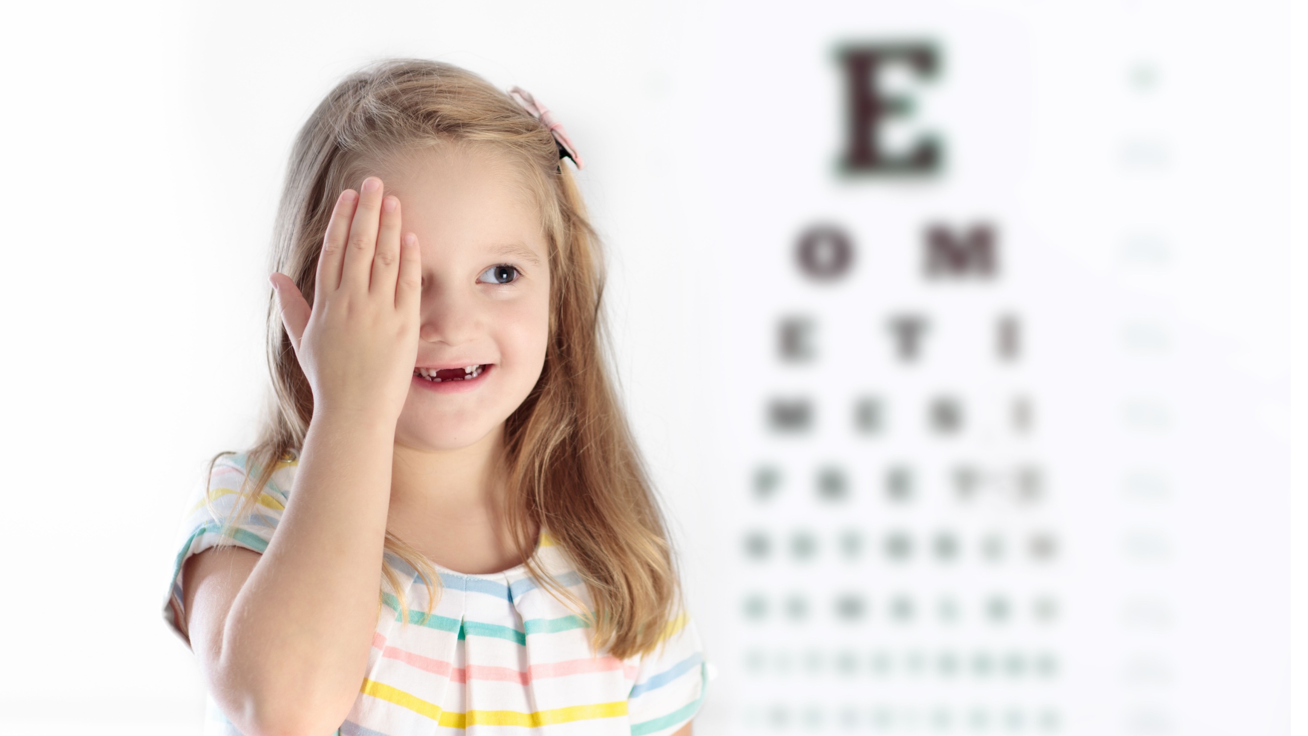 Child covering her eye at an eye exam.