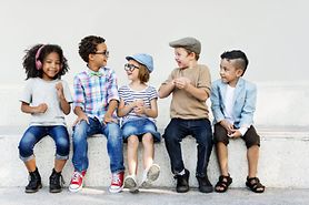 Group of diverse kids with glasses on, sitting on a bench.