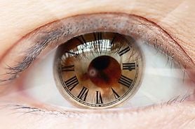 closeup of eye with roman numerals clock.