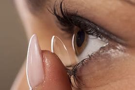 Woman placing contact lens on eye