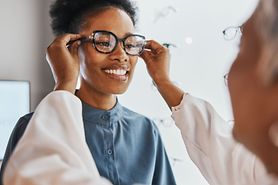 A woman getting fitted for eyeglasses at her optician's office, with special attention to frame temple size.