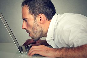 Man squints at laptop screen without reading glasses