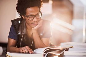 man wearing Foster Grant reading glasses while reading a book