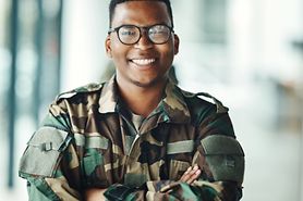 A smiling man in a military uniform wearing glasses.