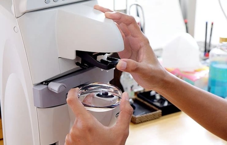 Person working with eyeglass machine.
