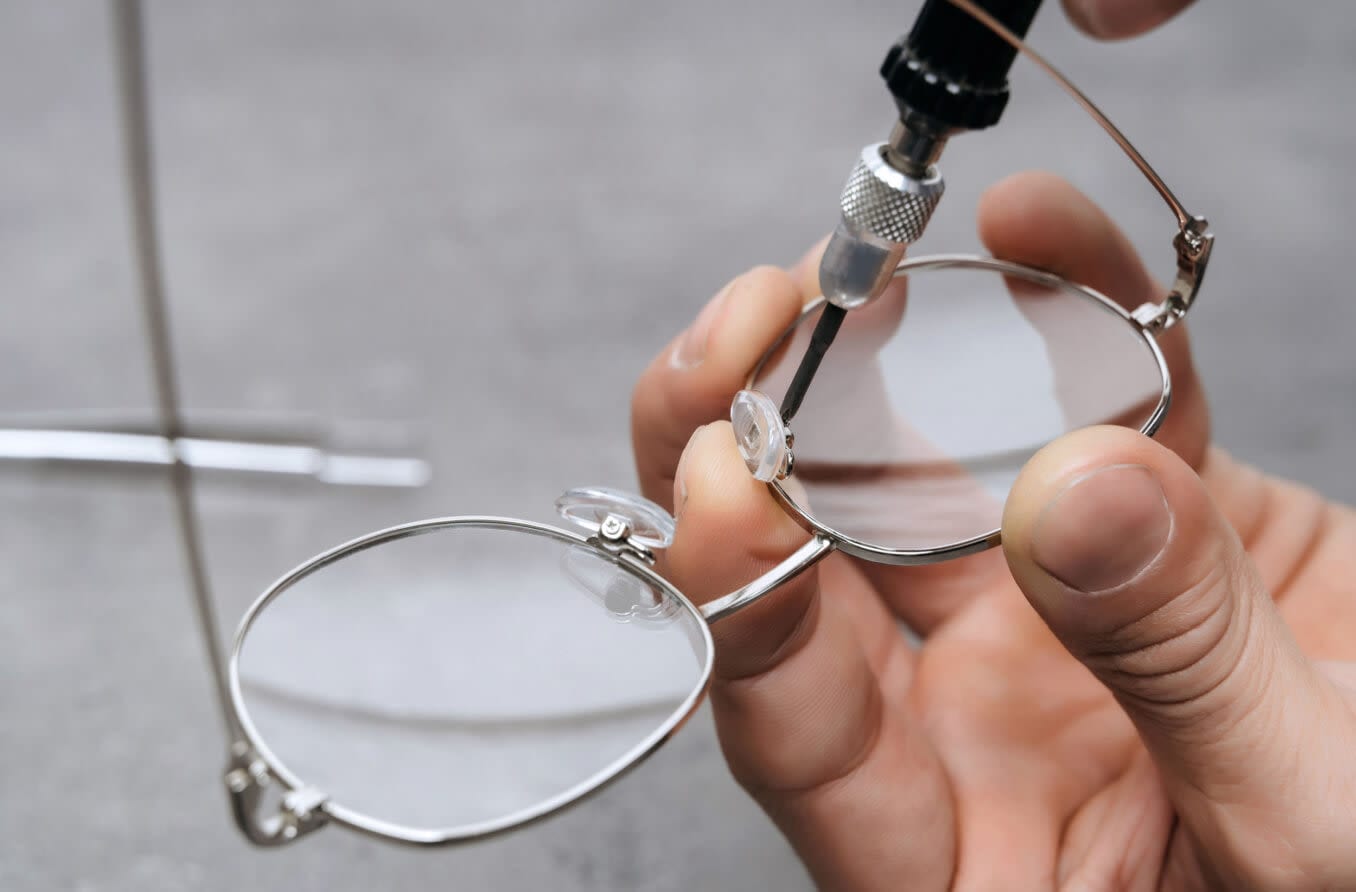 Person repairing broken eyeglass nose pads. Person repairing broken eyeglass nose pads.