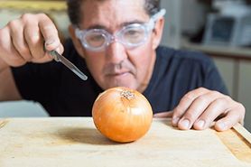 man cutting an onion wearing onion goggles
